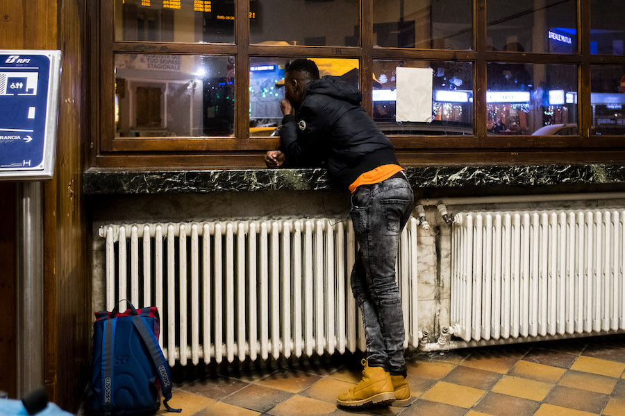 Un exilé dans la gare de Bardonecchia. Des citoyens solidaires lui donneront des chaussures et des  vêtements chauds