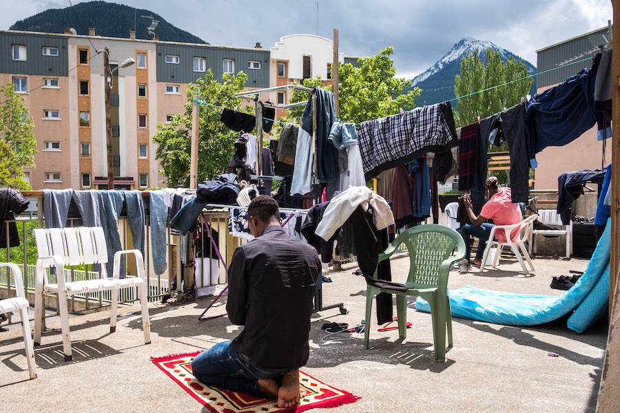 Un rifugiato prega sulla terrazza del rifugio solidale di Briançon.