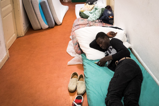 Un giovane migrante si riposa nel corridoio del Rifugio solidale di Briançon.
