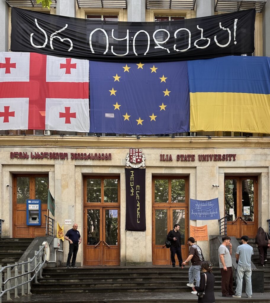 Tiflis, Juni 2026. Der Haupteingang der Ilia-Staatsuniversität. Auf dem schwarzen Banner steht „Nicht zu verkaufen!“. | Foto ©GpA